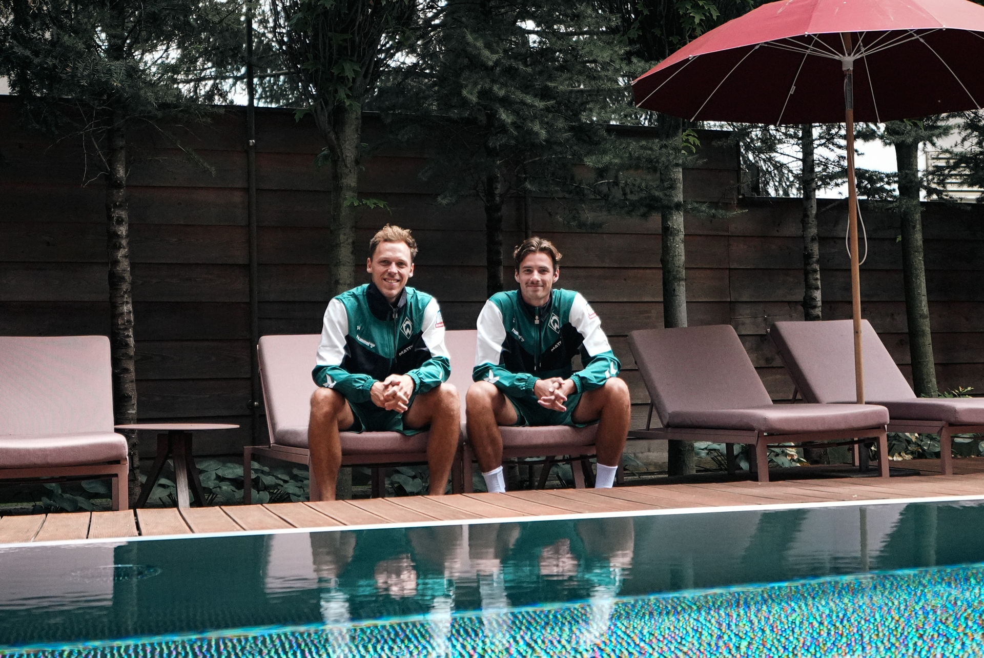 Senne Lynen und Olivier Deman sitzen im Hotel am Pool.