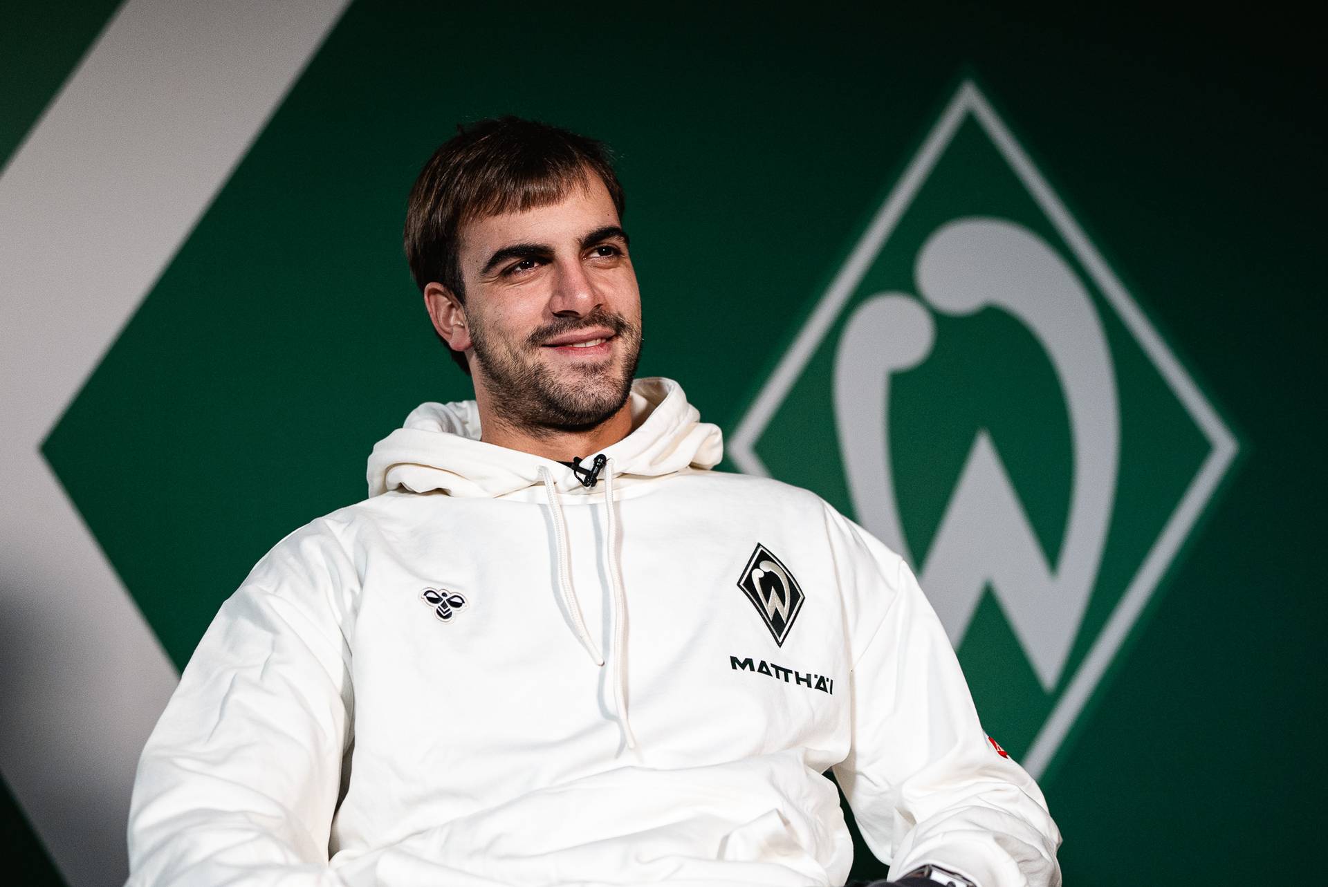 Jovan Milosevic sitzt vor einer Werder-Raute.