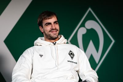 Milosevic sitzt auf einem Stuhl vor der Werder-Raute.