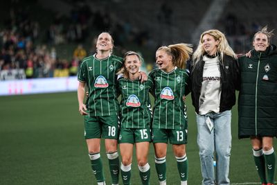 Die Spielerinnen lächeln und sind eingehakt.