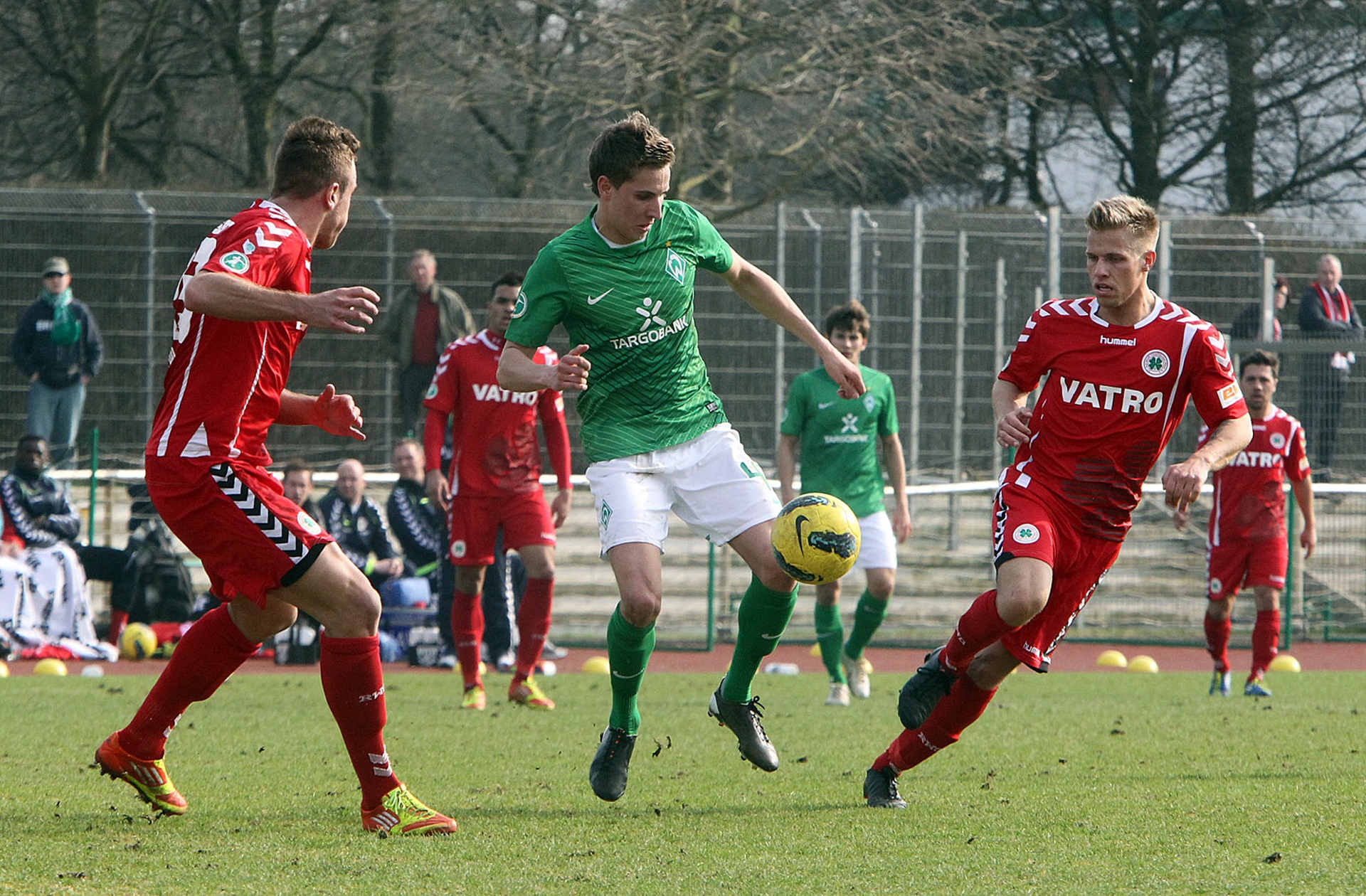 Marcus Mlynikowski führt den Ball und wird dabei von zwei gegnerischen Spielern eingekreist.