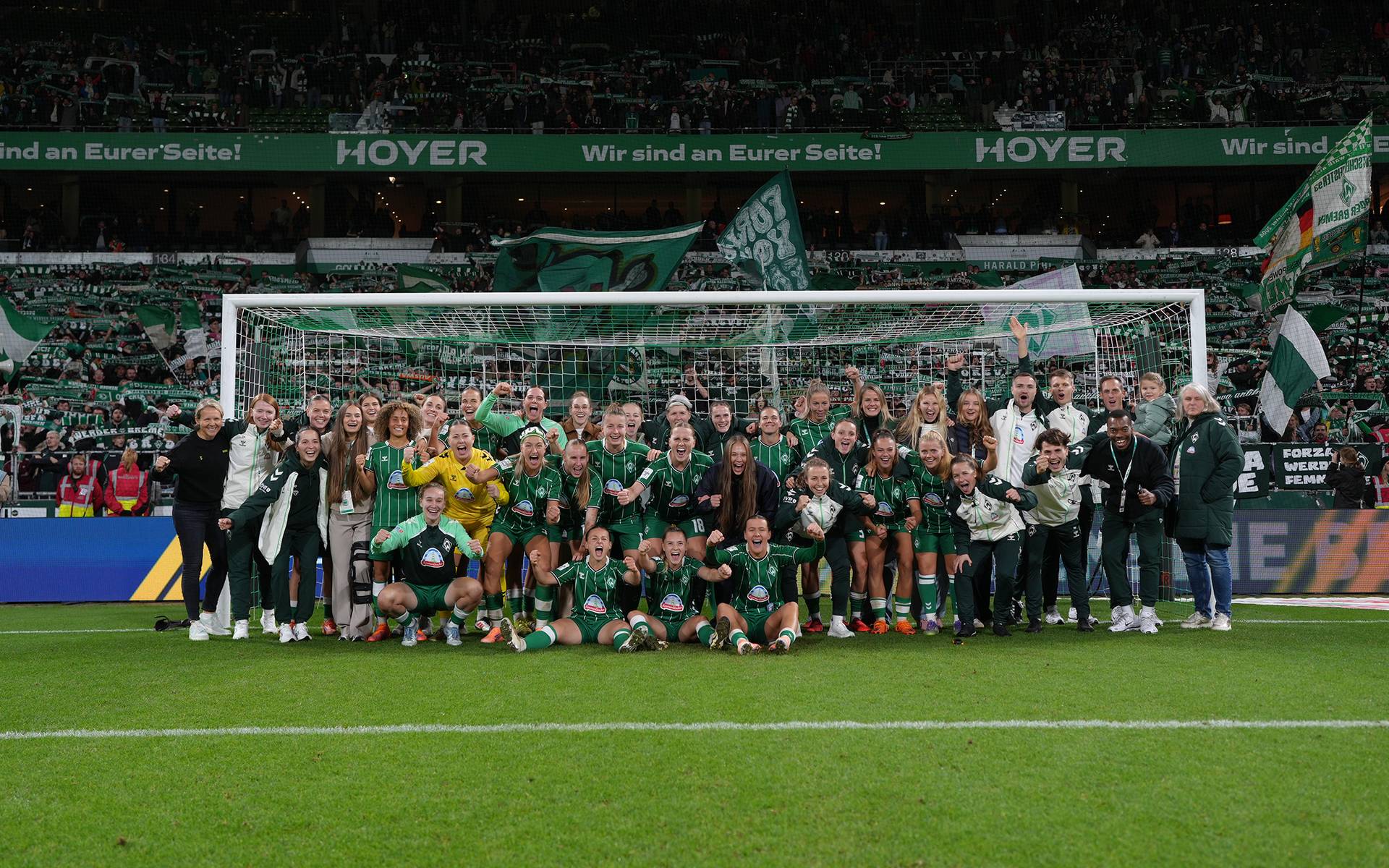 Die Mannschaft und der Staff stehen im Tor vor der Ostkurve.
