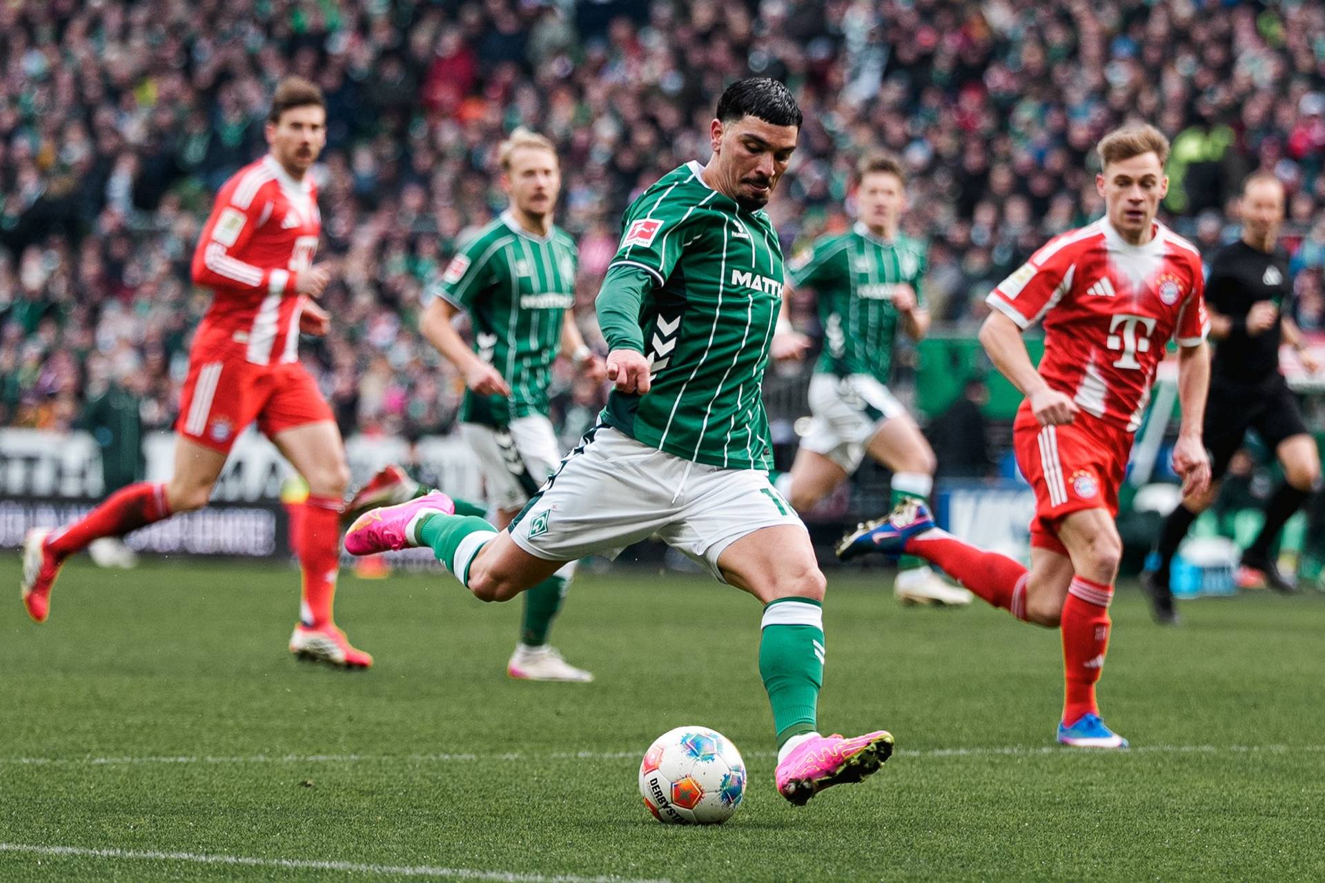 Cameron Puertas schießt. Im Hintergrund laufen links und rechts von ihm zwei Bayern-Spieler.