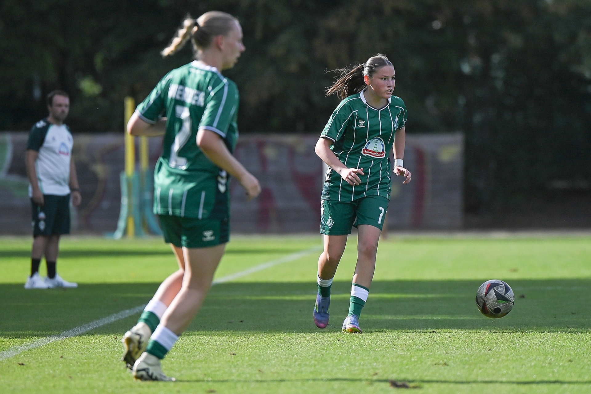 Zwei U17-Spielerinnen blicken in ihren grünen Trikots auf den Ball.