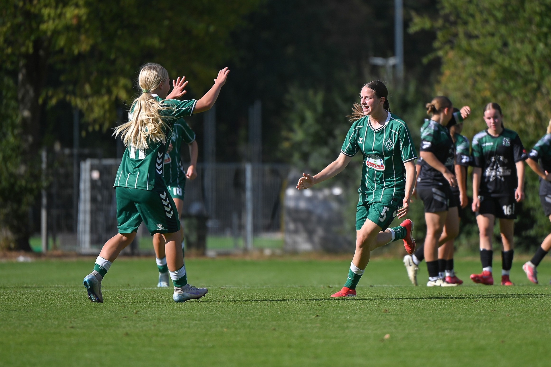 Zwei Spielerinnen im grünen Dress laufen jubelnd aufeinander zu
