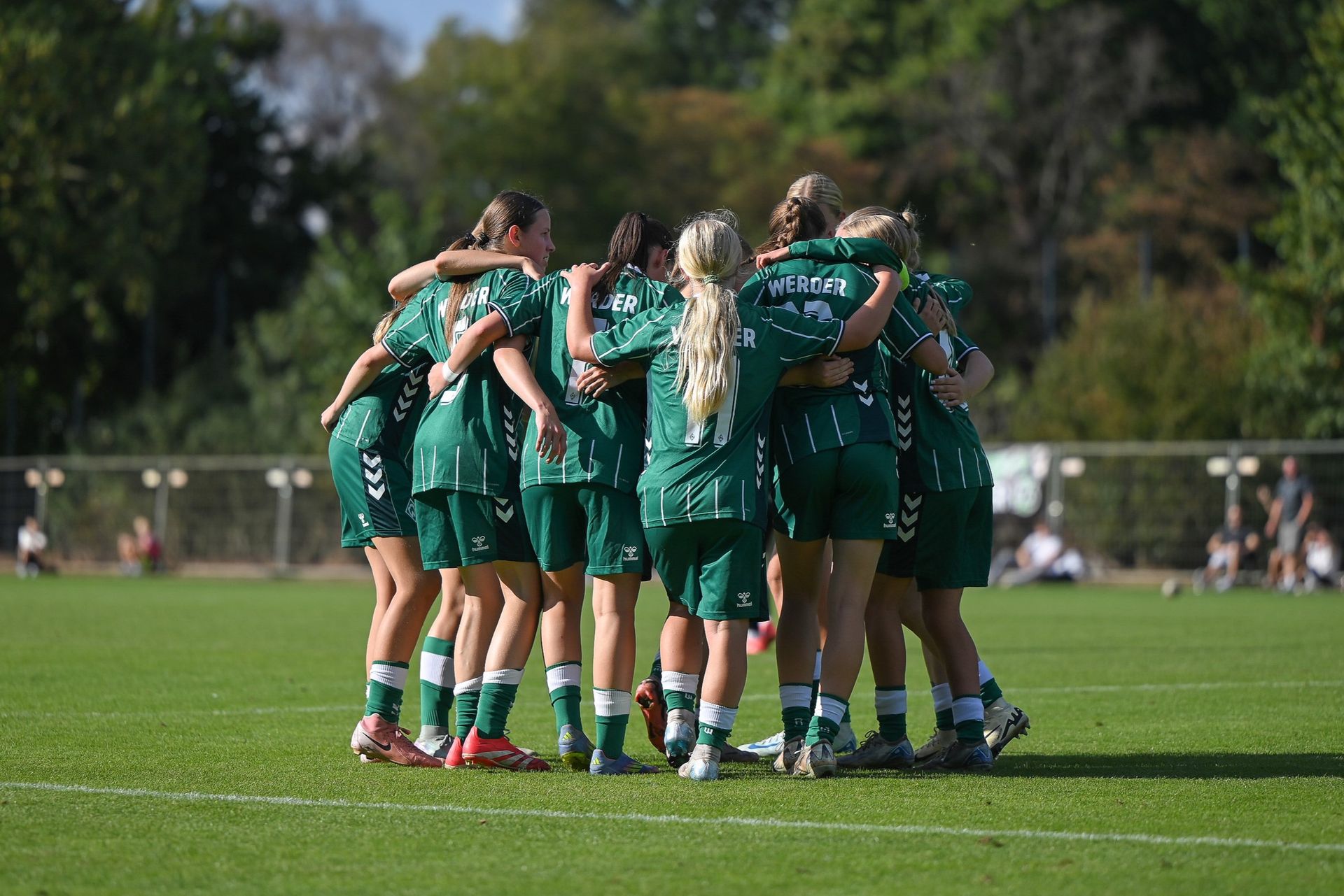 Die U17-Juniorinnen stehen mit grünem Werderdress in einem Mannschaftskreis.