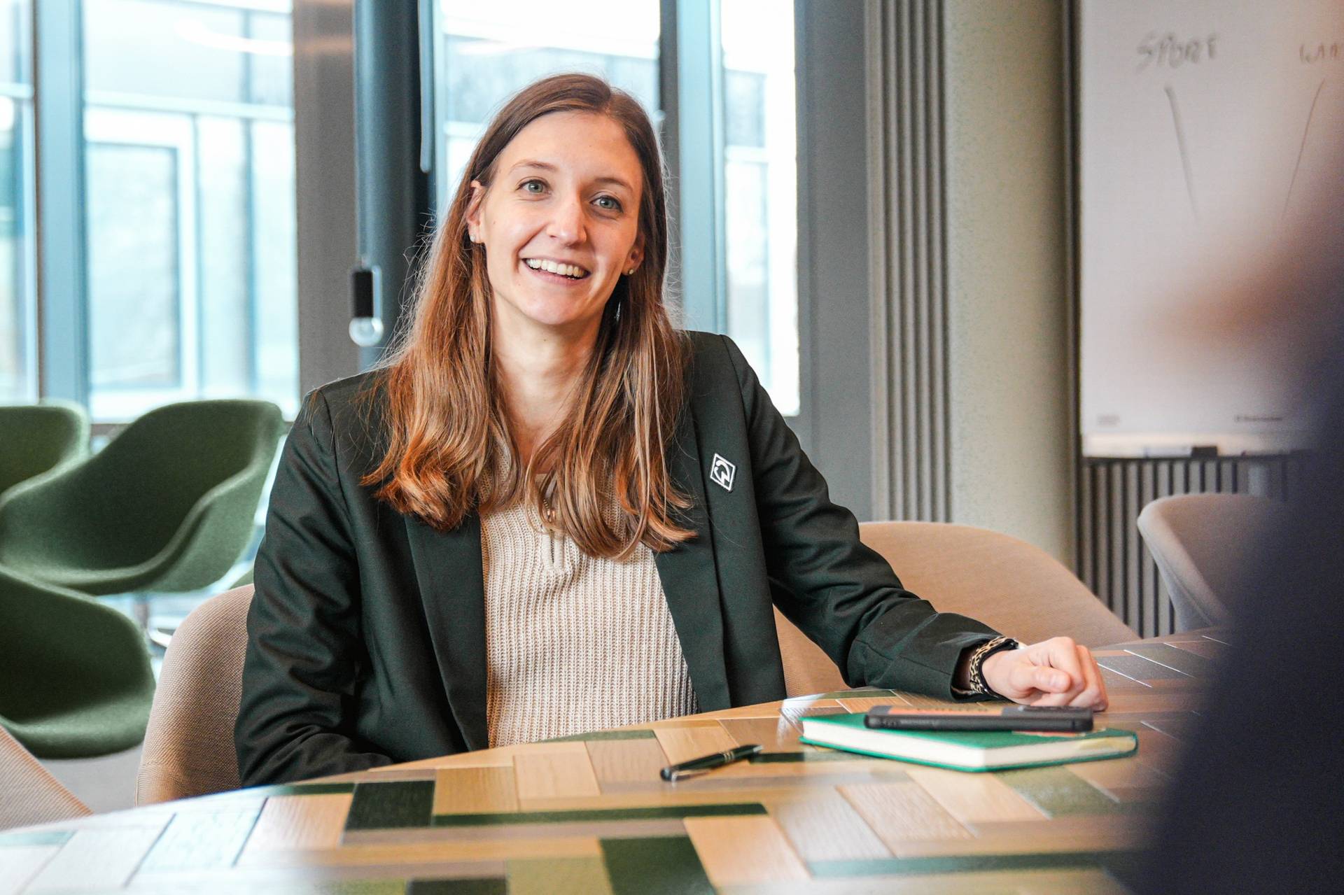 Finja Thormann sitzt an einem Tisch und lächelt in die Kamera.