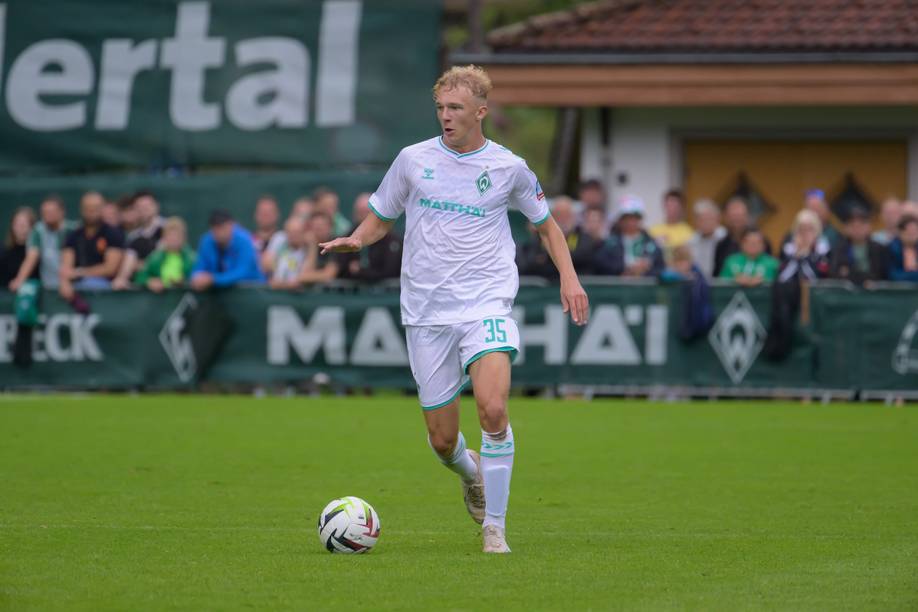 Leon Opitz dribbelt im weißen Werder-Trikot mit dem Ball am Fuß.