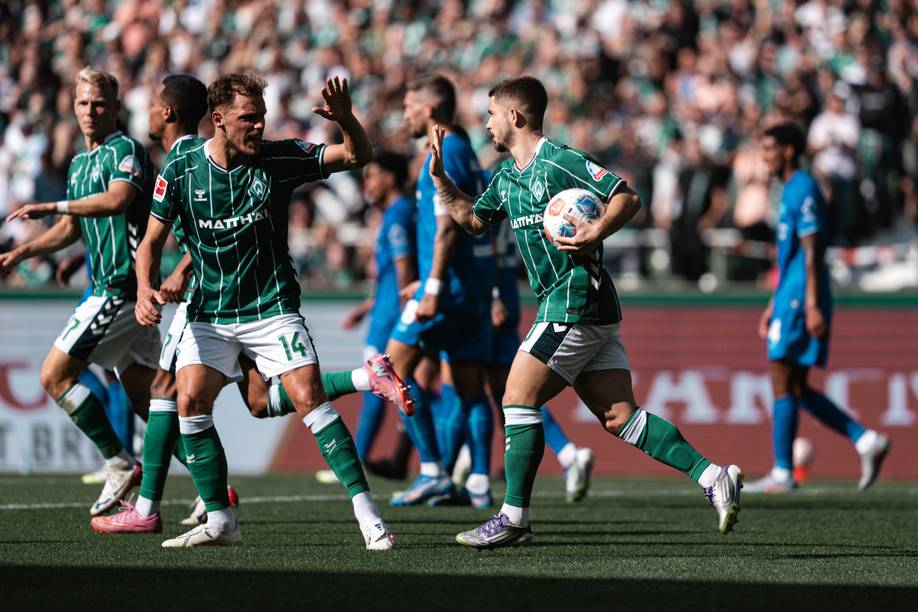Senne Lynen und Romano Schmid im grün-weißen Werder-Trikot freuen sich. Schmid trägt einen Ball unterm Arm.