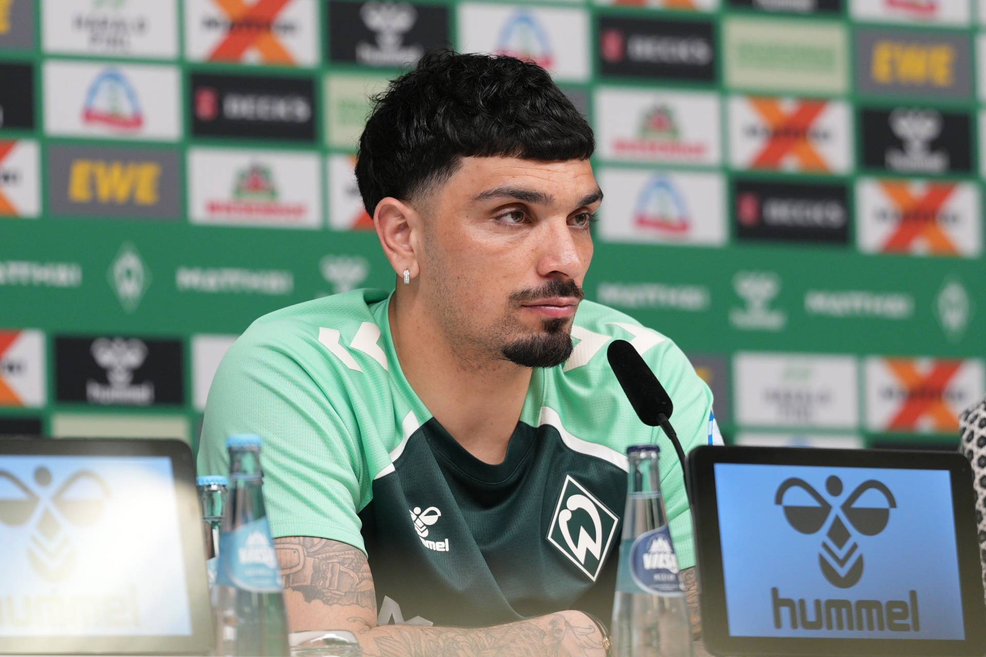 Cameron Puertas sitzt am Mikro auf der PK-Bühne.