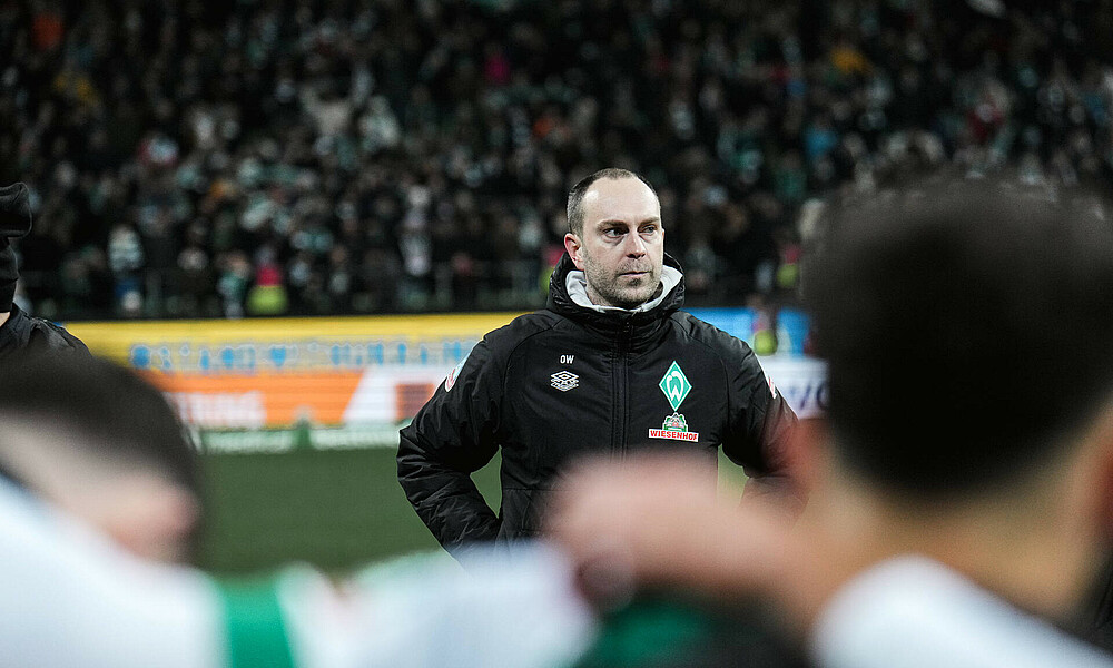 null Ole Werner schaut nachdenklich, stehend im Mannschaftskreis.