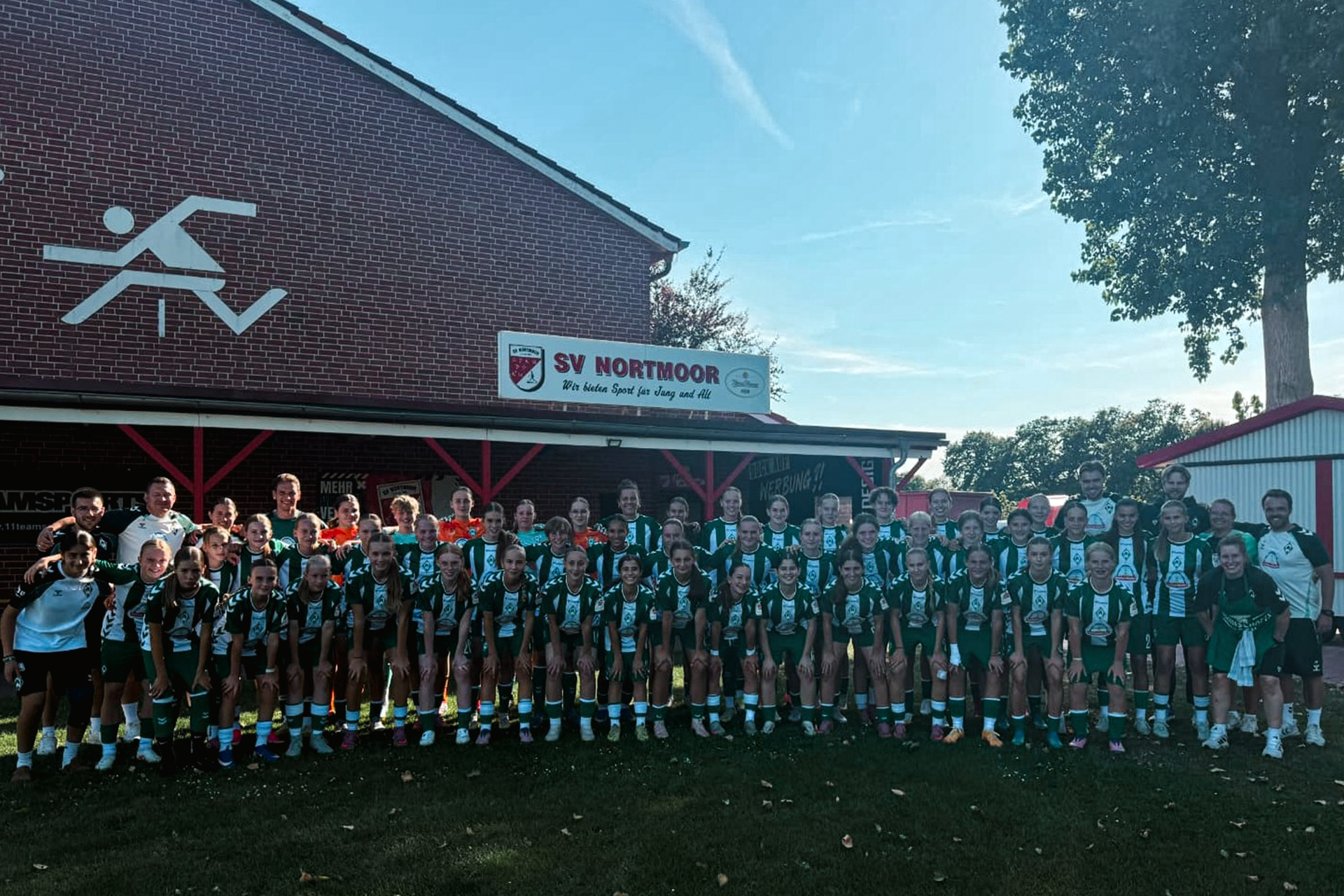Die U17 steht im grün-weiß gestreiften Heimtrikot über drei Reihen verteilt und lächelt für das Mannschaftsfoto in die Kamera.