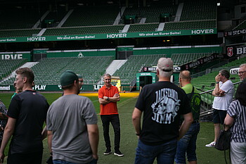 Frank Baumann steht vor einer Gruppe im wohninvest WERSERSTADION
