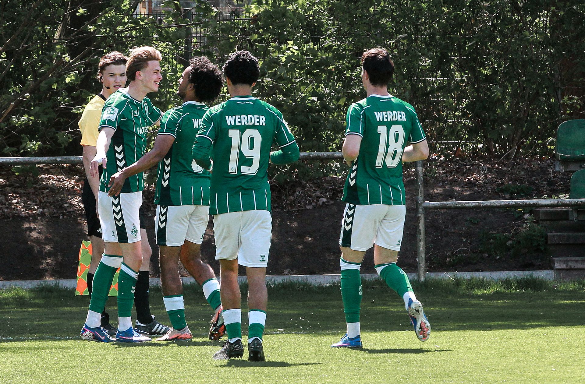 Vier Spieler der U19 laufen lachend aufeinander zu.