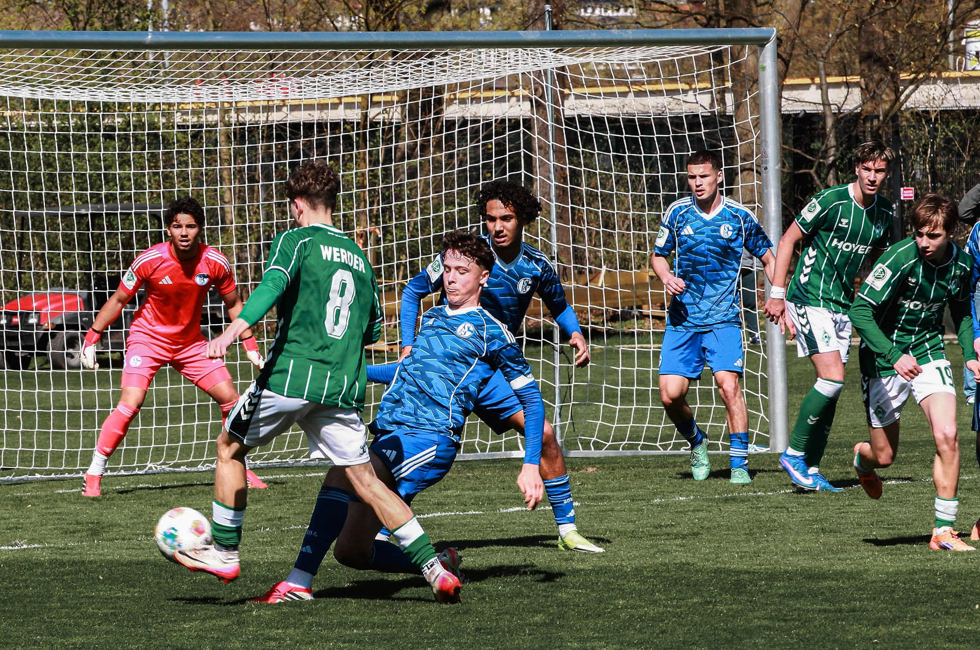 Ein Spieler von der U17 läuft mit dem Ball aufs Tor zu. Vor ihm grätscht ein Gegenspieler.