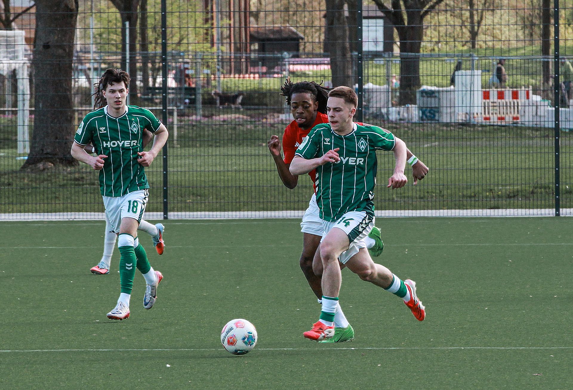 Ein Spieler von Werder Bremen läuft mit dem Ball und wird von einem Gegenspieler verfolgt.
