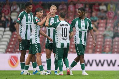 Fünf Werder-Spieler klatschen sich nach einem Tor ab und freuen sich.