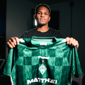 Felix Agu hält das neue Heimtrikot der Saison 2024/25 in die Kamera