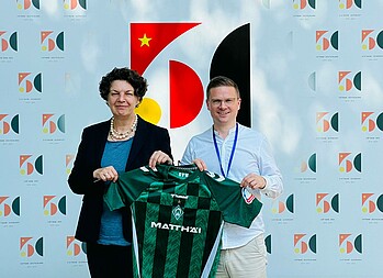 Helga Margarete Barth und Dominik Kupilas halten ein Werder-Trikot