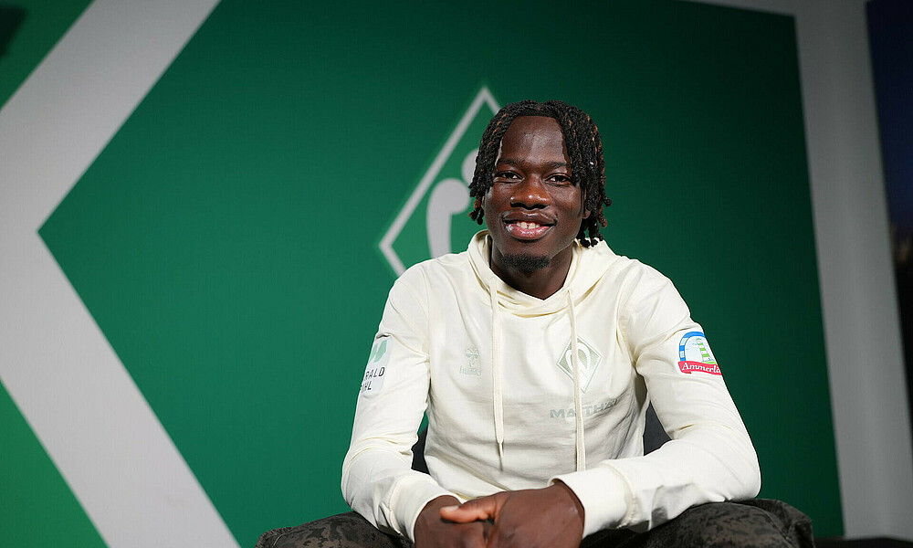 null Issa Kaboré vor einer grünen Wand.