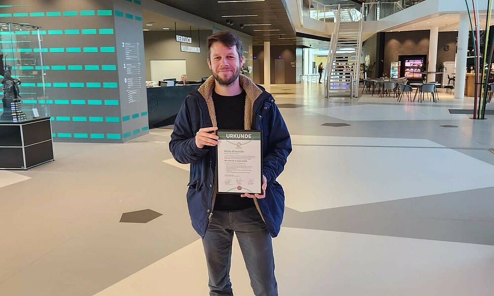 null Micha Alexander hält seine Urkunde hoch.