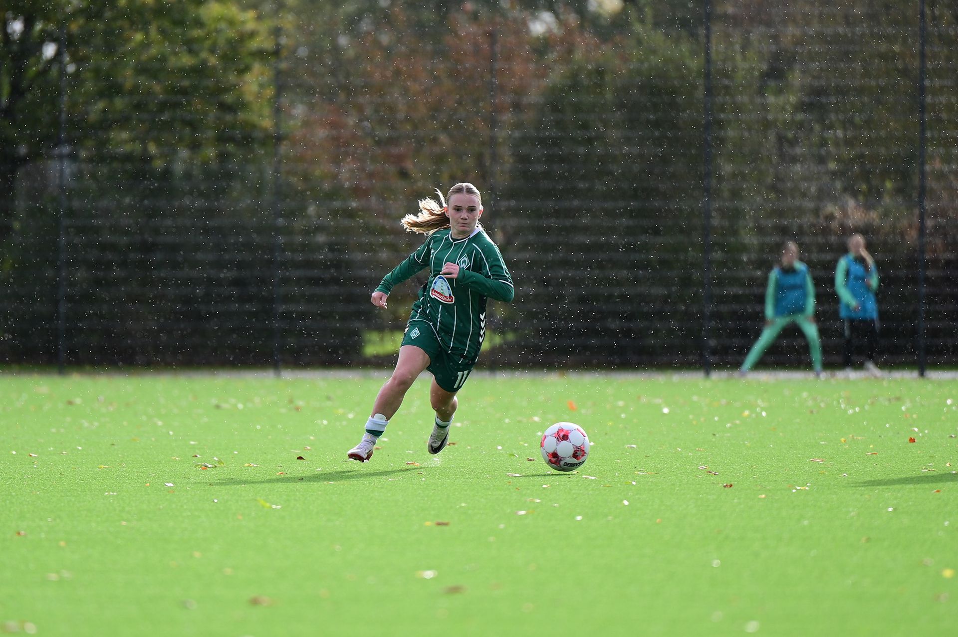 Eine Juniorinnen-Spielerin läuft mit dem Ball am Fuß über das Spielfeld