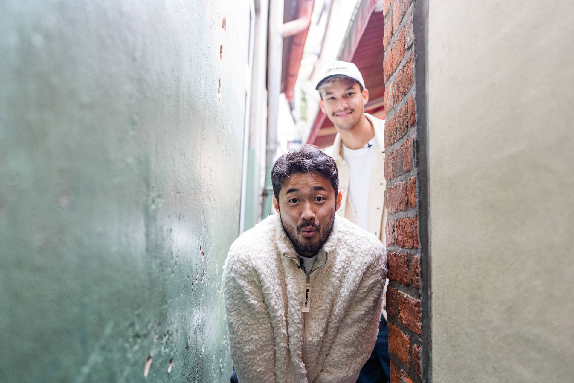 Yukinari Sugawara und Mio Backhaus in einer kleinen Gasse in der Stadt.