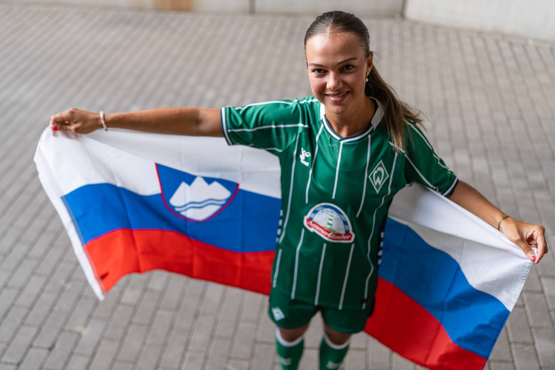 Maja Sternad im Heimtrikot hält hinter dem Rücken eine slowenische Flagge.