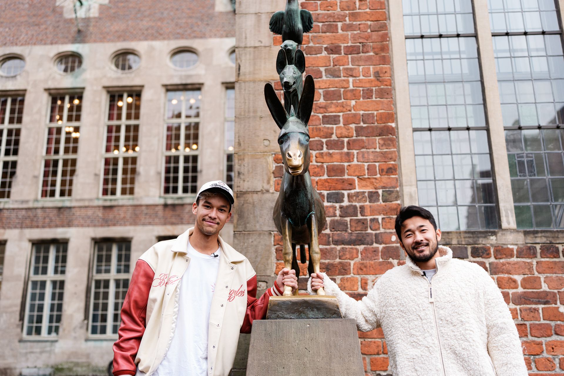 Mio Backhaus und Yukinari Sugawara fassen die Hufen des Esels der Bremer Stadtmusikanten an.