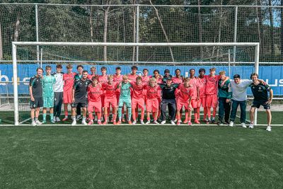 Die U16 steht vor einem Tor, umarmt sich und lächelt in die Kamera.