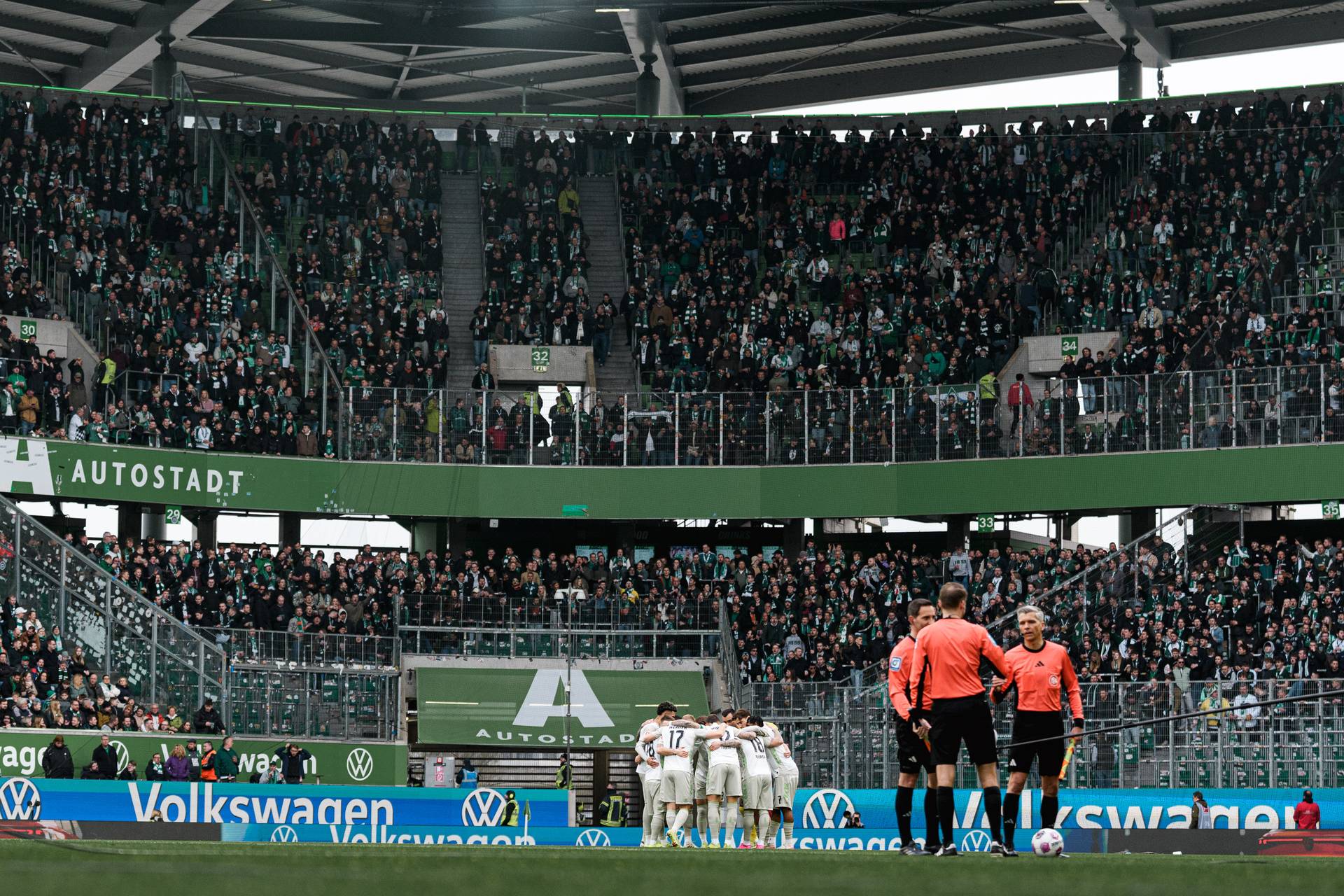 Die Mannschaft steht im Kreis vor der der halbleeren Gästekurve.