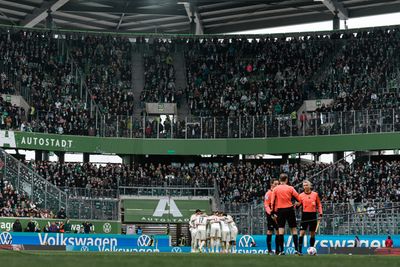 Die Mannschaft steht im Kreis vor der halbgefüllten Gästekurve.