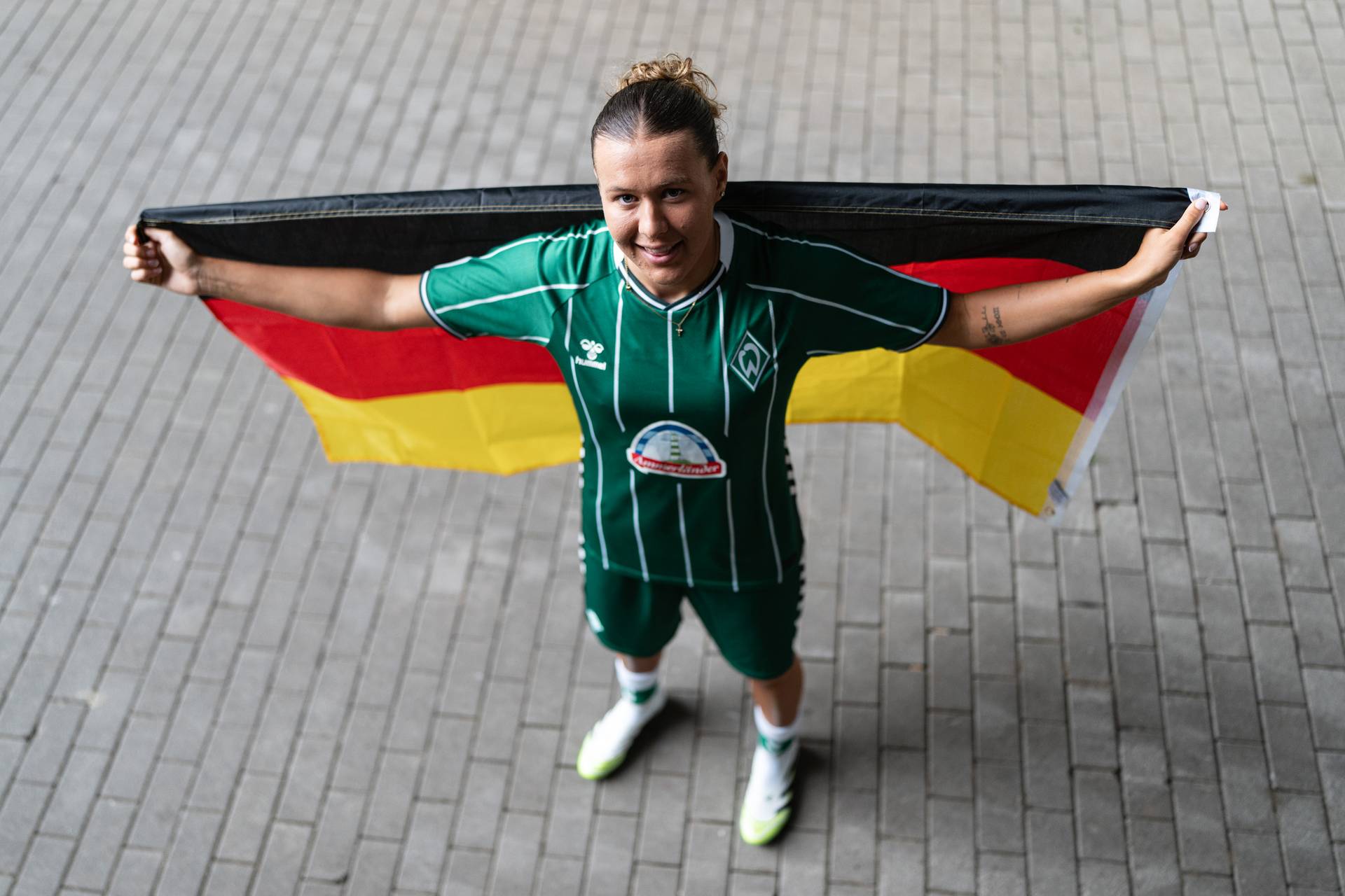 Larissa Mühlhaus hält hinter sich die Deutschland-Flagge hoch.