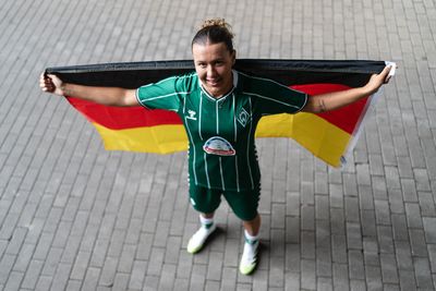 Larissa Mühlhaus hält hinter sich die Deutschland-Flagge hoch.