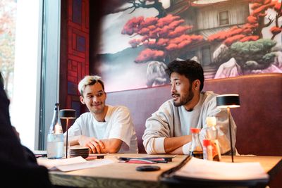 Mio Backhaus und Yukinari Sugawara sitzen in einem Restaurant an einem Tisch.