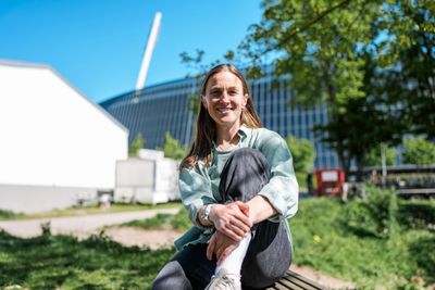 Michaela Brandenburg sitzt vor dem Weserstadion auf einer Bank und lächelt in die Kamera.