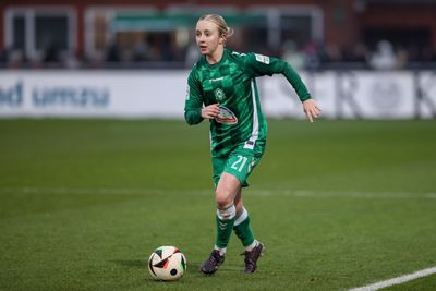 Caro Siems in grünem Trikot dribbelt einen Ball auf dem Spielfeld, konzentriert und in Aktion während eines Spiels.