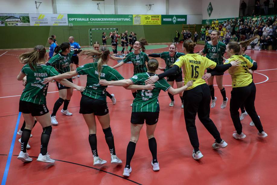 Die Handballerinnen des SV Werder jubeln Arm in Arm im Kreis in der Halle.