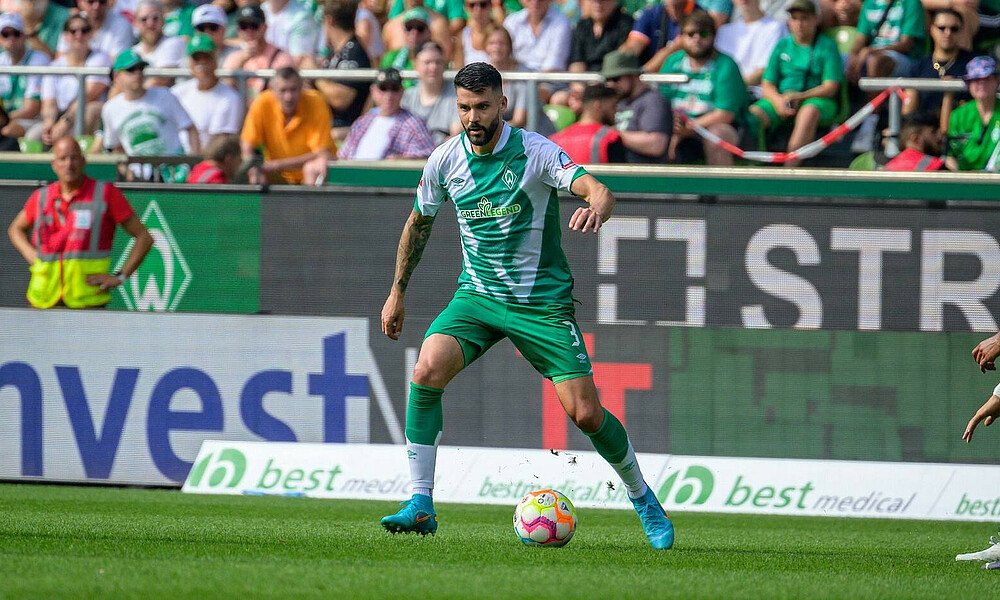 Anthony Jung am Ball, im Hintergrund sitzen Fans.