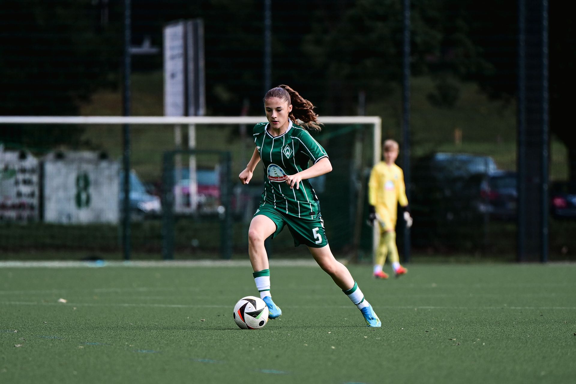 Eine U15-Spielerin im grünen Dress dribbelt mit dem Ball