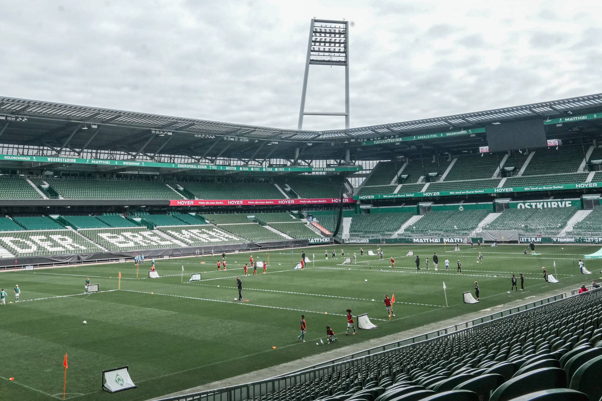 Ein Bild von der Südribüne aus. Auf dem heiligen Rasen spielen Kinder Fußball.