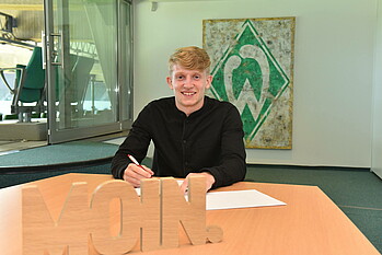 Jan-Niklas Beste lächelt bei seiner Vertragsuntezeichnung in die Kamera.