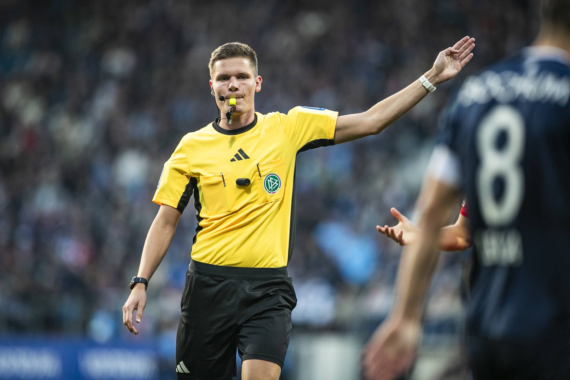 Schiedsrichter Dr. Florian Exner mit der Pfeife im Mund.