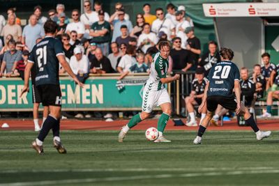 Jakob Wiehe spielt einen Pass, während er von Gegenspielern umringt ist.