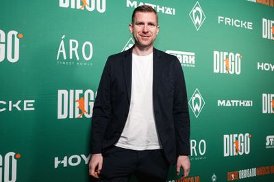 Per Mertesacker im Anzug vor einer Werbewand.