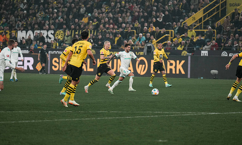 Bittencourt mit Ball am Fuß vor Marco Reus. 