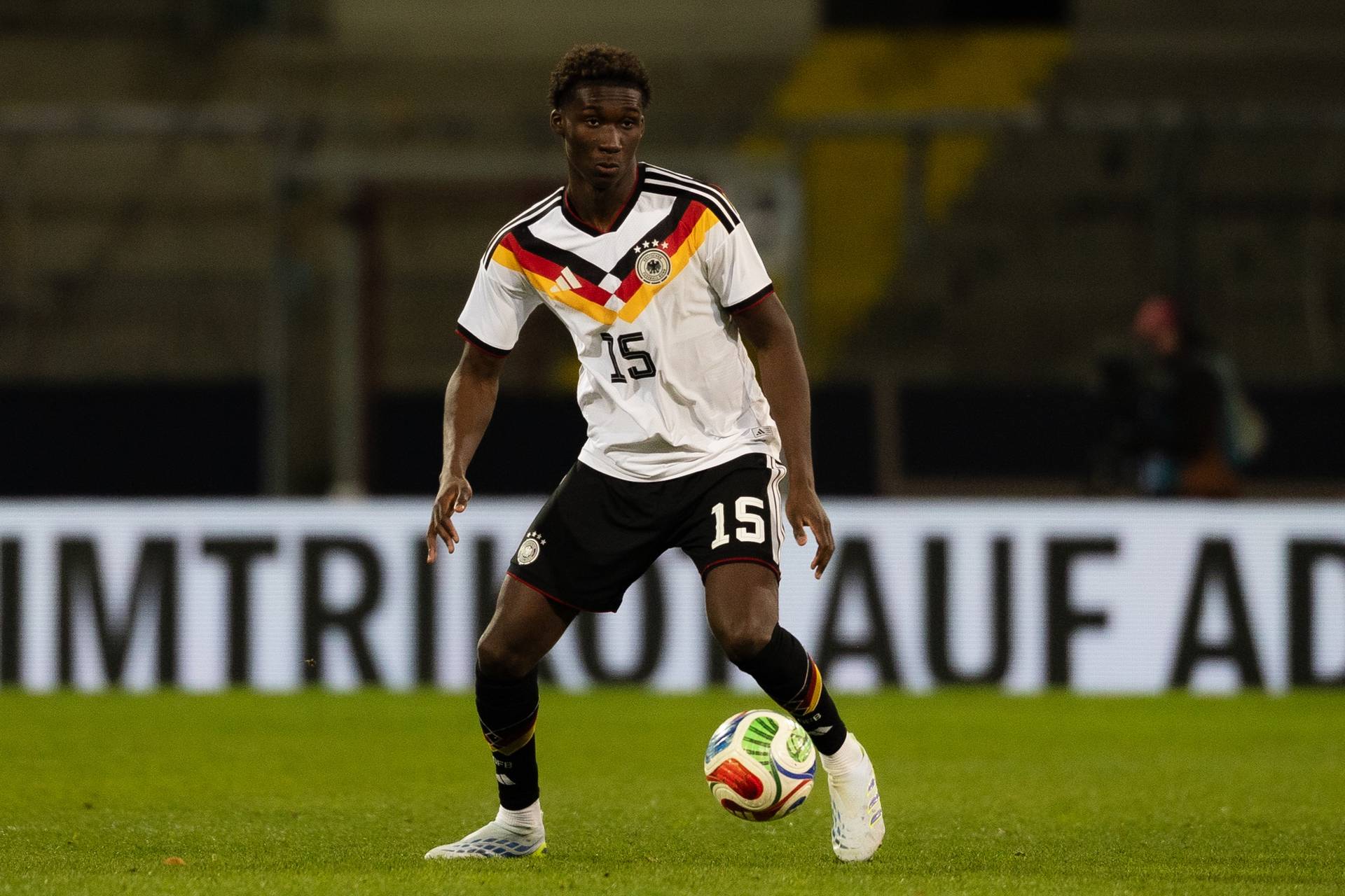 Karim Coulibaly im DFB-Trikot. Er hat den Ball vor sich und schaut nach einer Anspielstation.