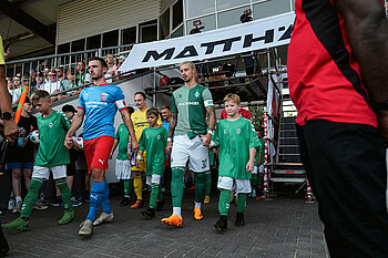 Marco Friedl läuft mit einem Einlaufkind auf den Platz. 