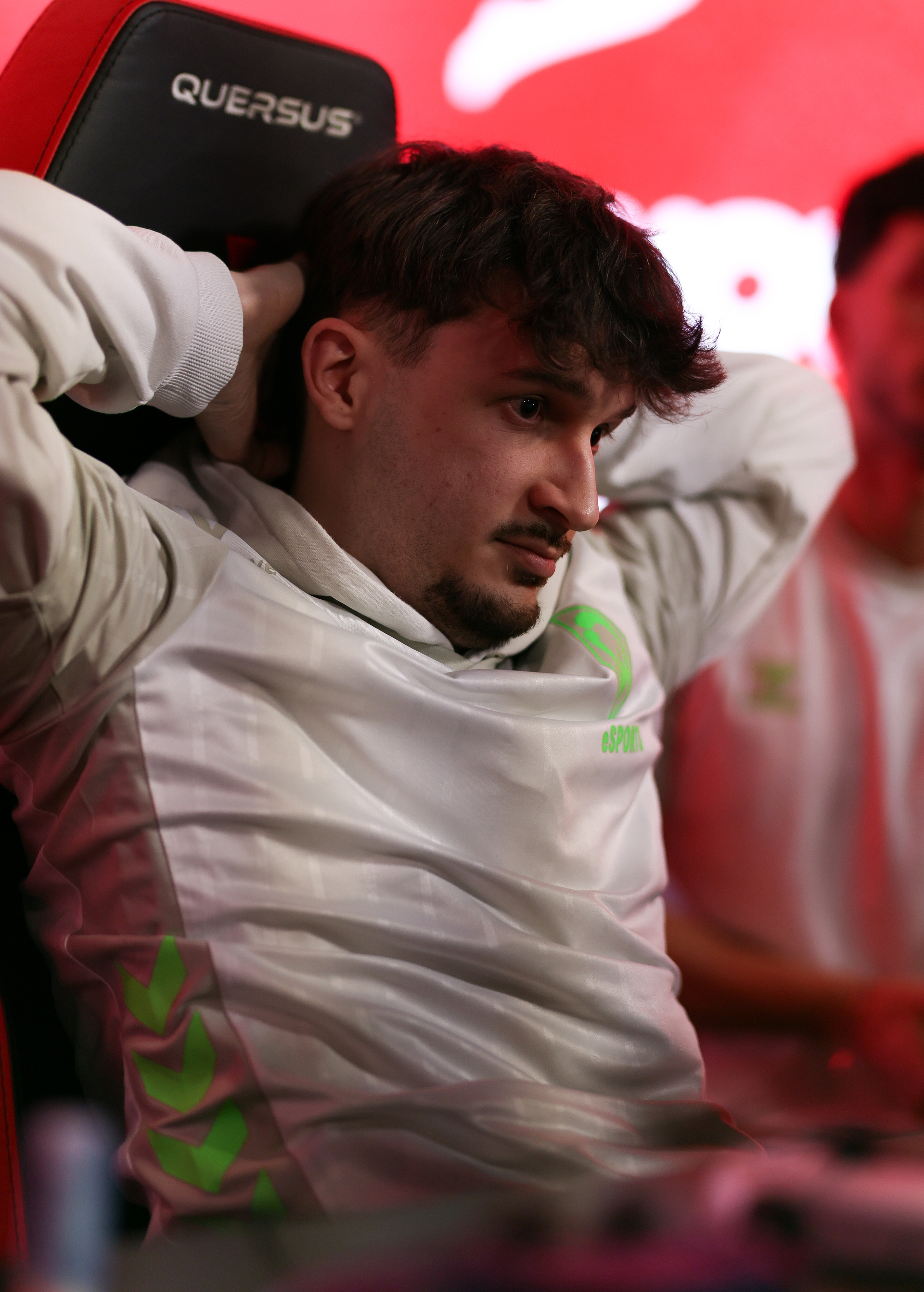 Ein eFootballer sitzt in seinem Stuhl und hat die Arme hinter dem Kopf verschränkt.