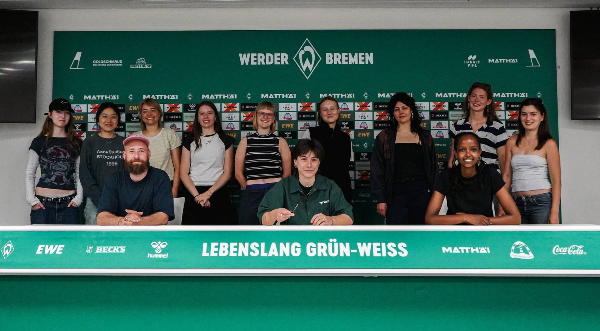 Die HfK Studierenden sitzen hinter dem Tisch der Pressekonferenzen im Weserstadion